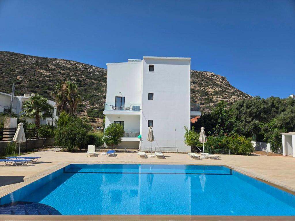 Outdoor pool of Paradise Matala Hotel with sun loungers and umbrellas